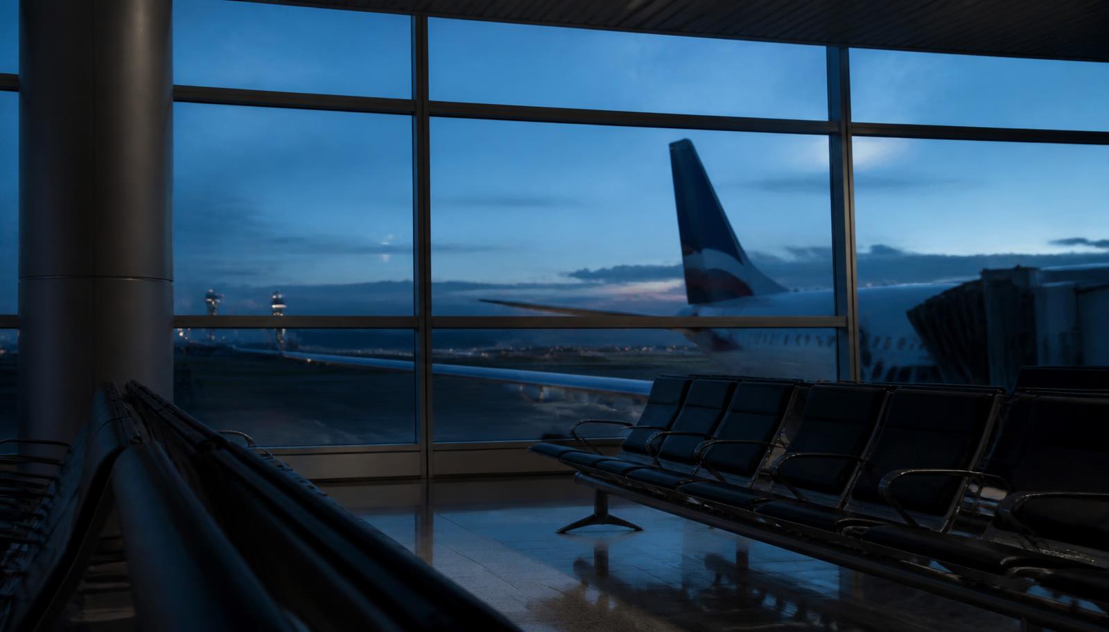 Sala de embarque de aeroporto ao anoitecer com aeronave estacionada ao fundo